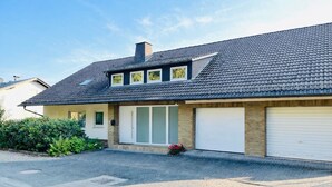 Une maison d’habitation avec un toit en pente, un garage et une porte d’entrée.