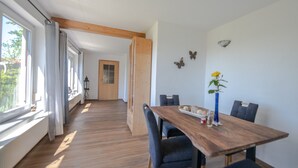 Un coin repas avec une table en bois, des chaises bleues, un vase avec une fleur jaune et des décorations murales en forme de papillons.