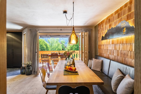 A dining area with a wooden table, bench seating, and a hanging light fixture.
