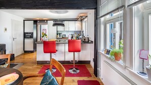 A modern kitchen with white cabinets, a central island, and red bar stools.