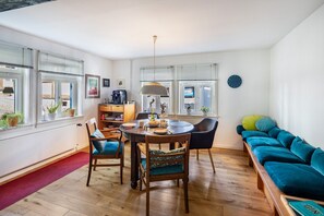 Un salon moderne comprenant un coin repas, un plancher en bois, un canapé et une table à manger avec des chaises.