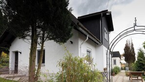 Un bâtiment blanc avec un toit noir, une porte en métal et un banc au premier plan.