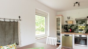 Eine kleine Küche mit Essbereich, ein Fenster mit Ausblick und ein Schrank mit Geschirr.