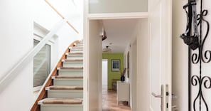 A staircase with carpeted steps leading to a room with a green wall and a door with a decorative handle.
