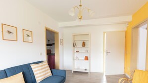 A living room with a blue sofa, a white bookshelf, and a yellow wall. - Apartment 'Ferienwohnung Kleiber' with Shared Terrace, Shared Garden and Wi-Fi (Schotten)