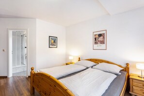 A double bed with wooden headboard, a bedside table with a lamp, and a framed picture on the wall.