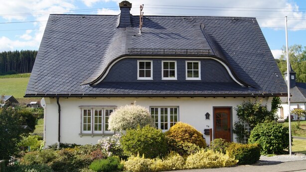 A two-story house with a dark slate roof, white exterior walls, and a small front porch. - Apartment "Kebben" with Shared Terrace, Garden, and Pool (Kirchhundem)