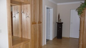 Ein Zimmer mit Holzschränken, einer schwarzen Kommode und einer Tür zu einem weiteren Raum.
