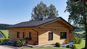 A wooden house with a sloped roof, a chimney, and a small porch with potted plants. - Chalet 'Landhaus Rachelblick' with Mountain View, Private Terrace and Wi-Fi (Eppenschlag)