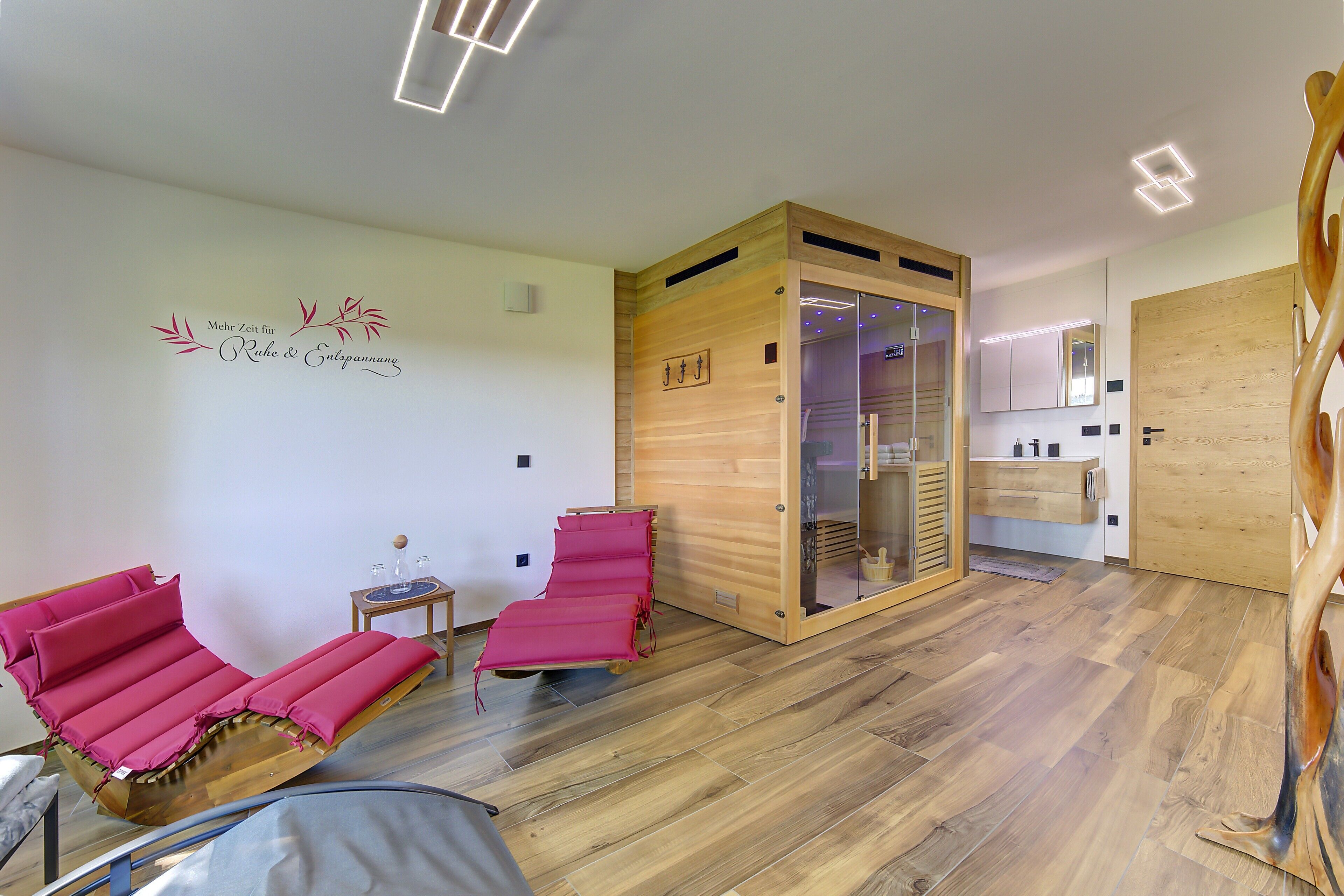 A room with two red reclining chairs, a wooden cabinet, and a mirror on the wall.