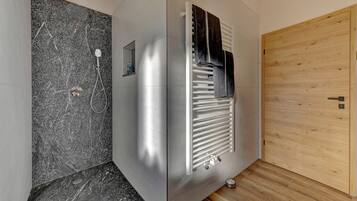 Ein Badezimmer mit Dusche, Handtuchhalter und Holztür.