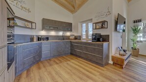 A modern kitchen with grey cabinets, a wooden floor, and a coffee machine. - Chalet 'Landhaus Rachelblick' with Mountain View, Private Terrace and Wi-Fi (Eppenschlag)