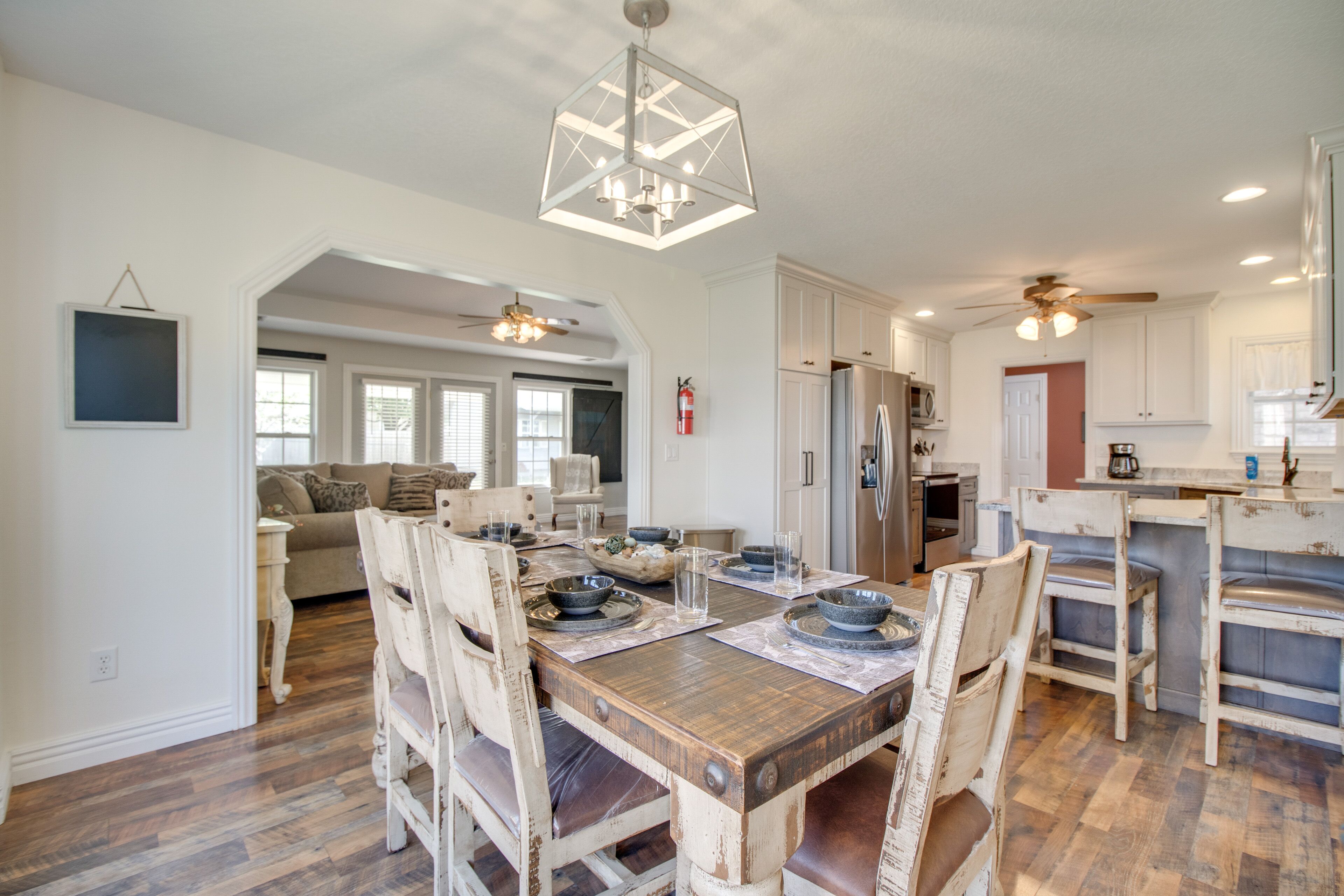 A spacious kitchen with a wooden dining table, white cabinets, and a ceiling fan.