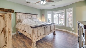 Ruime slaapkamer met groot bed, houten vloer en een plafondventilator.