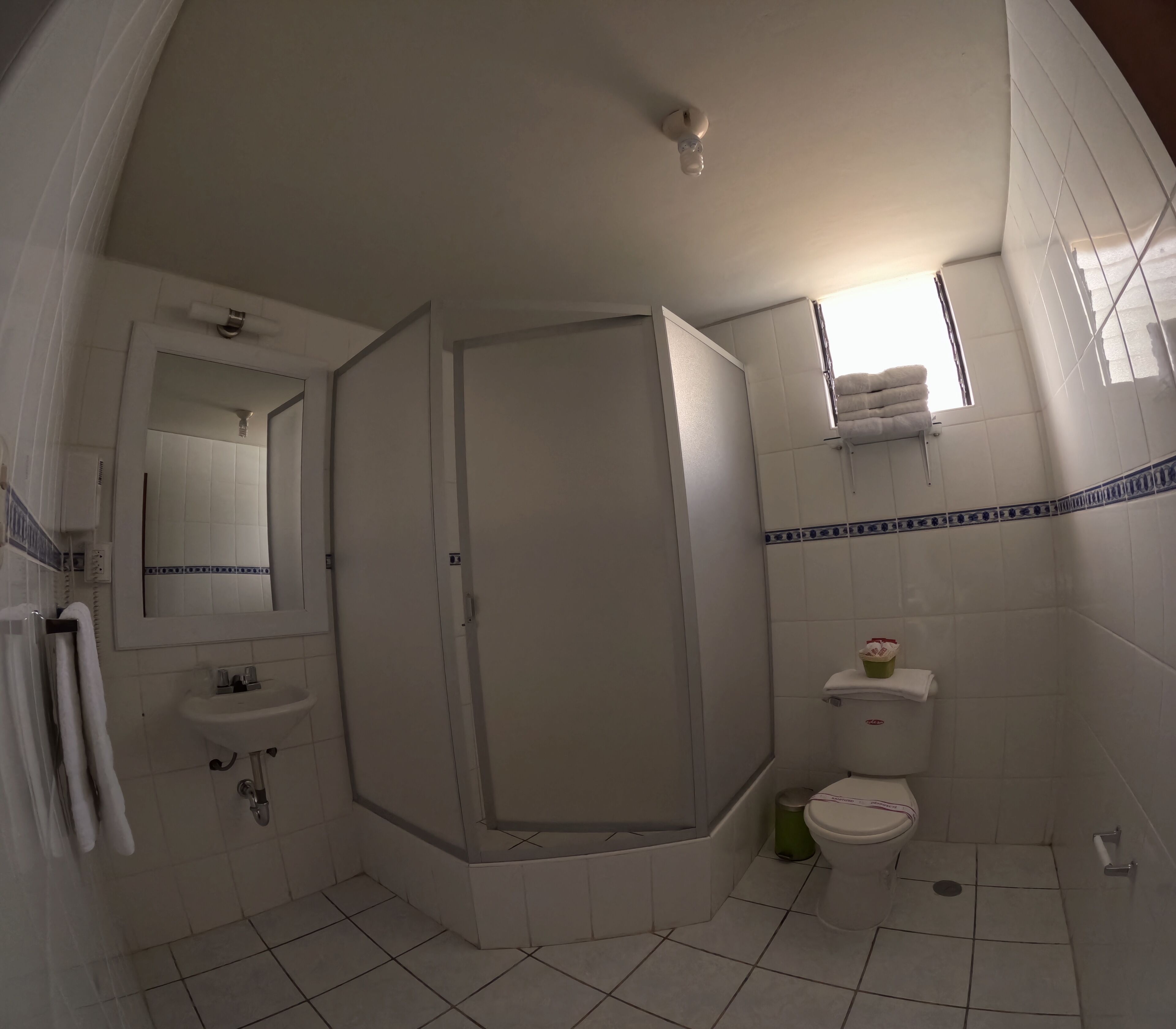 A bathroom with a shower, sink, toilet, and a mirror.