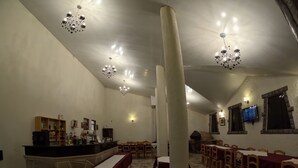 Un amplio comedor con suelo de mármol, varias mesas y candelabros colgantes.