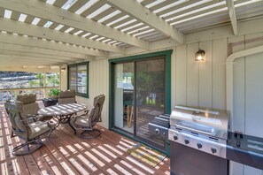Un patio al aire libre con una parrilla, asientos y vistas del paisaje circundante.