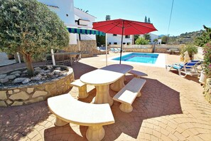 Relax by the pool in a serene outdoor space with a stone floor, round table, and lounge chairs.