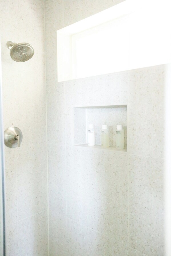A shower with a handheld showerhead and a shelf with toiletries. - Perch! Forested setting, ocean views! New interior (Neskowin)