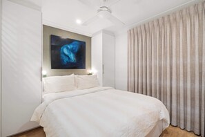 A bedroom with a bed, a ceiling fan, a painting on the wall, and a window with curtains. - Urban Sanctuary! 1Bed, 1Bath, 1Car, POOL~Teneriffe (Teneriffe)