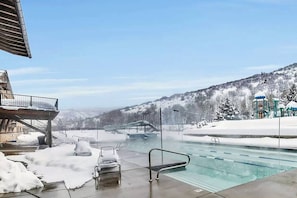 En swimmingpool med utsikt över ett snötäckt landskap och en byggnad med ett sluttande tak.