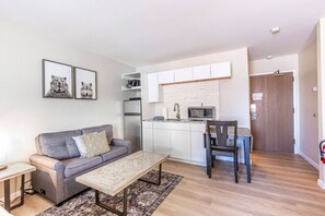 En modern lägenhet med ett litet kök, en soffa, ett matbord och en stol.