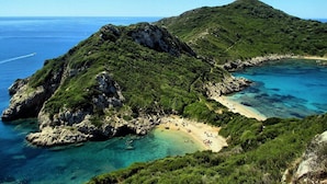 Un paisaje costero con una playa, acantilados rocosos y aguas azules cristalinas.