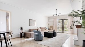 A modern living room with a sofa, armchair, coffee table, and a dining area with a table and chairs. - Chic & Luminous 3BR Apartment in Kifisia (Kifisia)