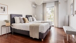 A modern bedroom with a large bed, bedside tables, a bench, and a view of the outdoors. - Chic & Luminous 3BR Apartment in Kifisia (Kifisia)