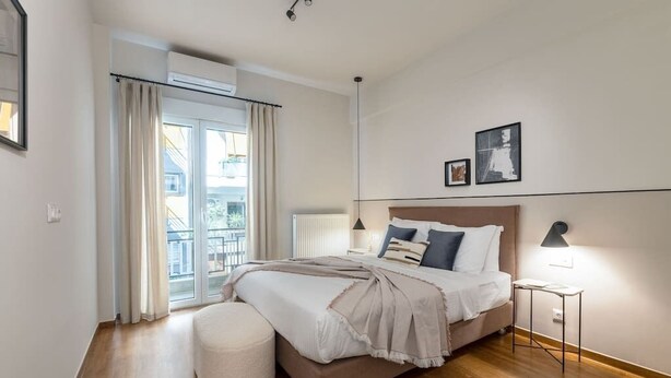 Un dormitorio con cama, mesita de noche, lámpara, ventana con cortinas y un radiador.