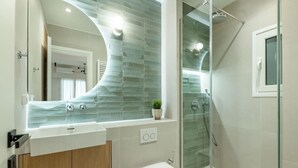 Un baño moderno con mampara de vidrio, un lavamanos blanco y un mueble de madera.