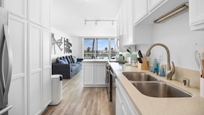 Cocina moderna con armarios blancos, lavamanos doble y vista al área de estar.