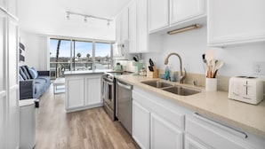 Una cocina moderna con armarios blancos, un amplio ventanal y vistas al exterior.