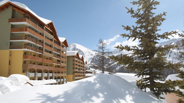 A multi-story hotel with balconies, snow-covered surroundings, and a mountainous backdrop. - Chalet in Isola with Scenic Views (LE HAMEAU)