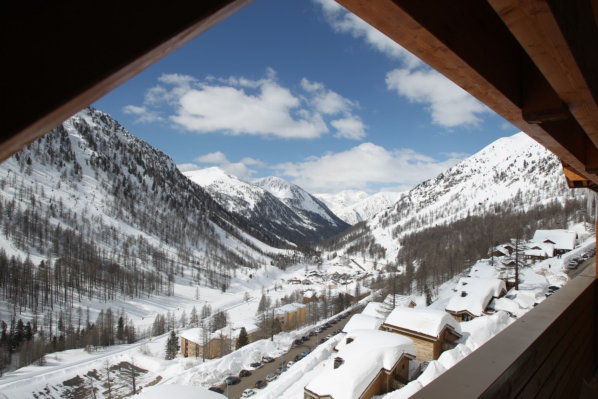 Ein verschneites Bergdorf mit Häusern und einer Skipiste.