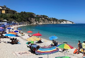 A crowded beach with numerous colorful umbrellas and people enjoying the seaside.