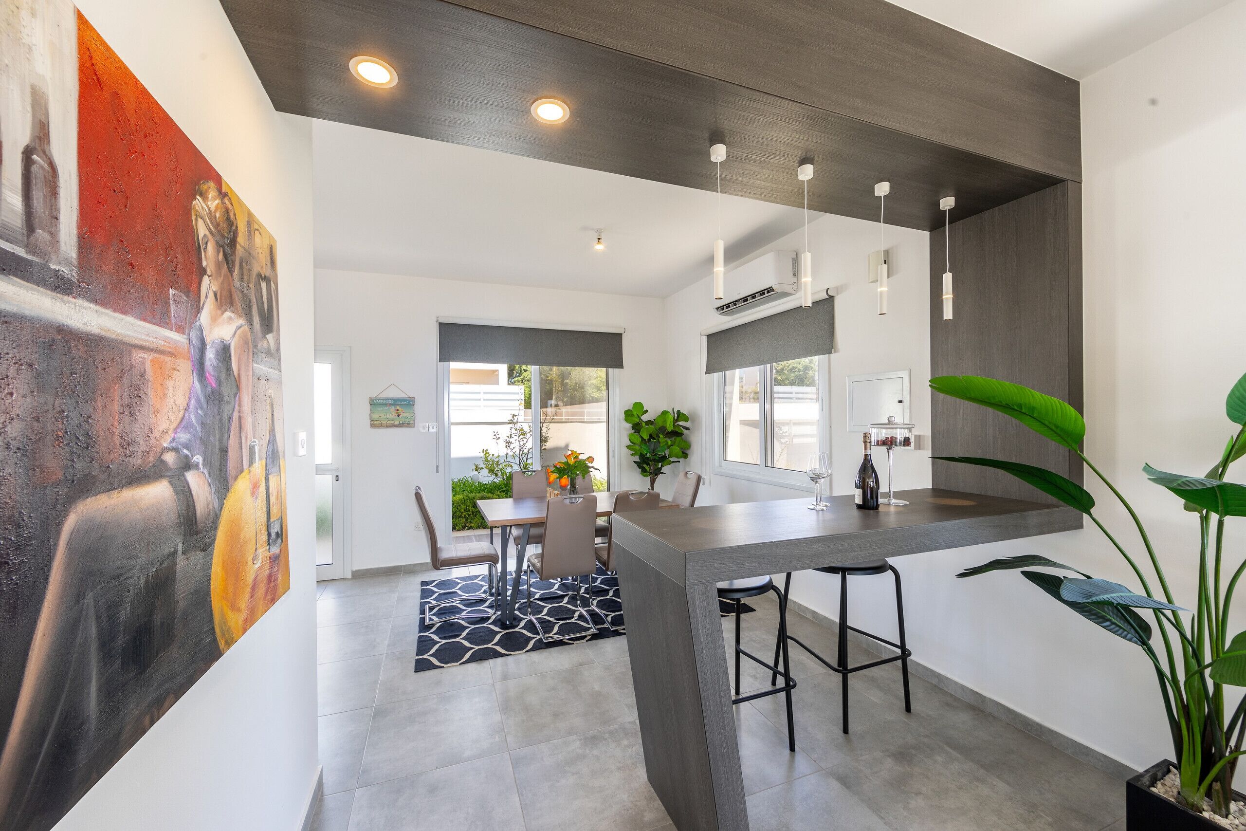 Une cuisine moderne dotée d’un îlot central, de tabourets de bar et d’un coin repas avec une table et des chaises.