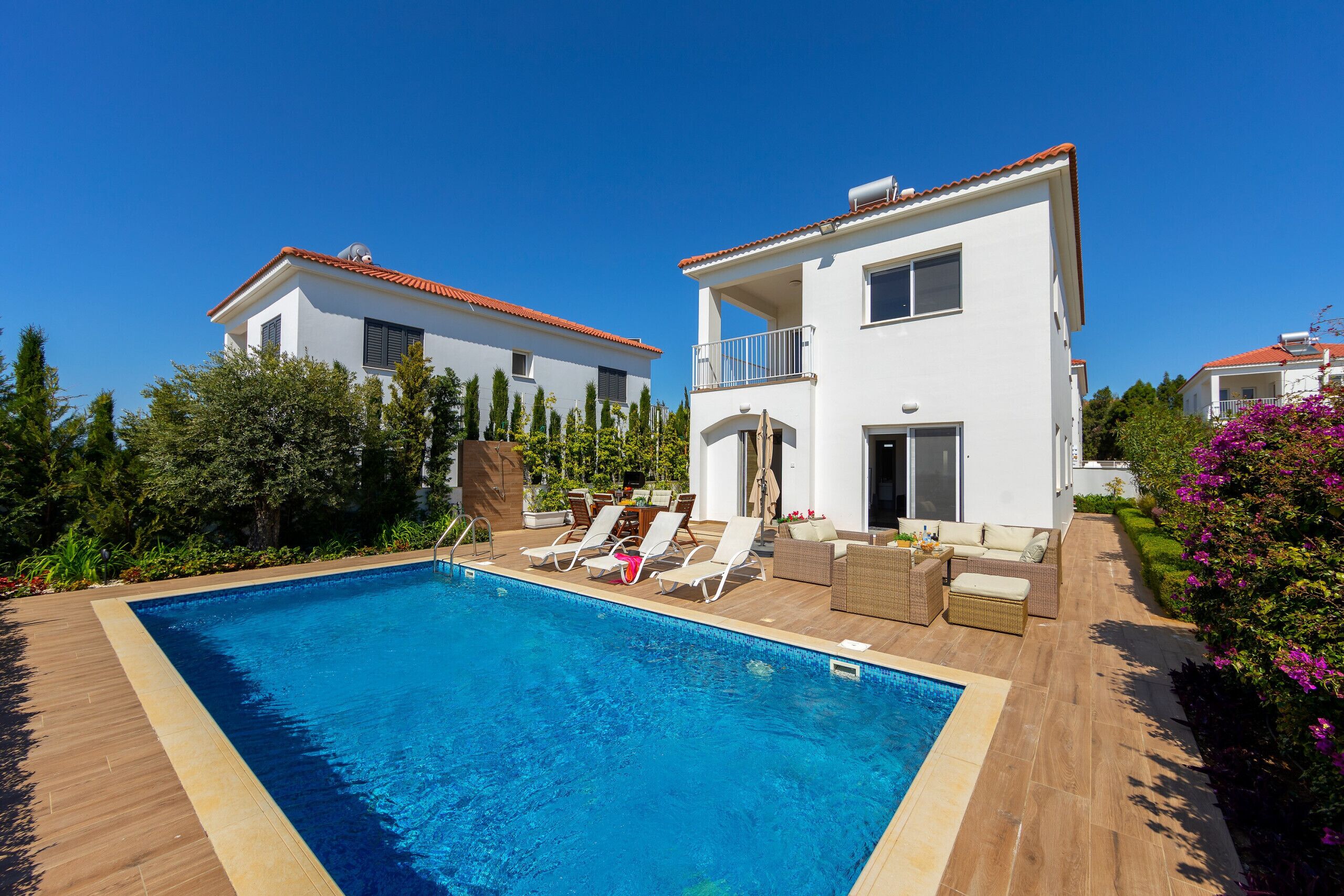 A modern two-story house with a swimming pool, outdoor seating, and a well-maintained garden.