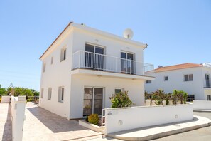 A two-story white building with a balcony, a satellite dish, and a small garden area. - Napa Bay View Villa 3 (Ayia Napa)