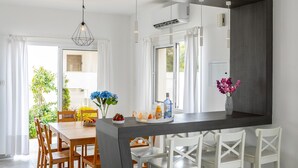 Een moderne keuken met een centraal eiland, witte stoelen en een eettafel.
