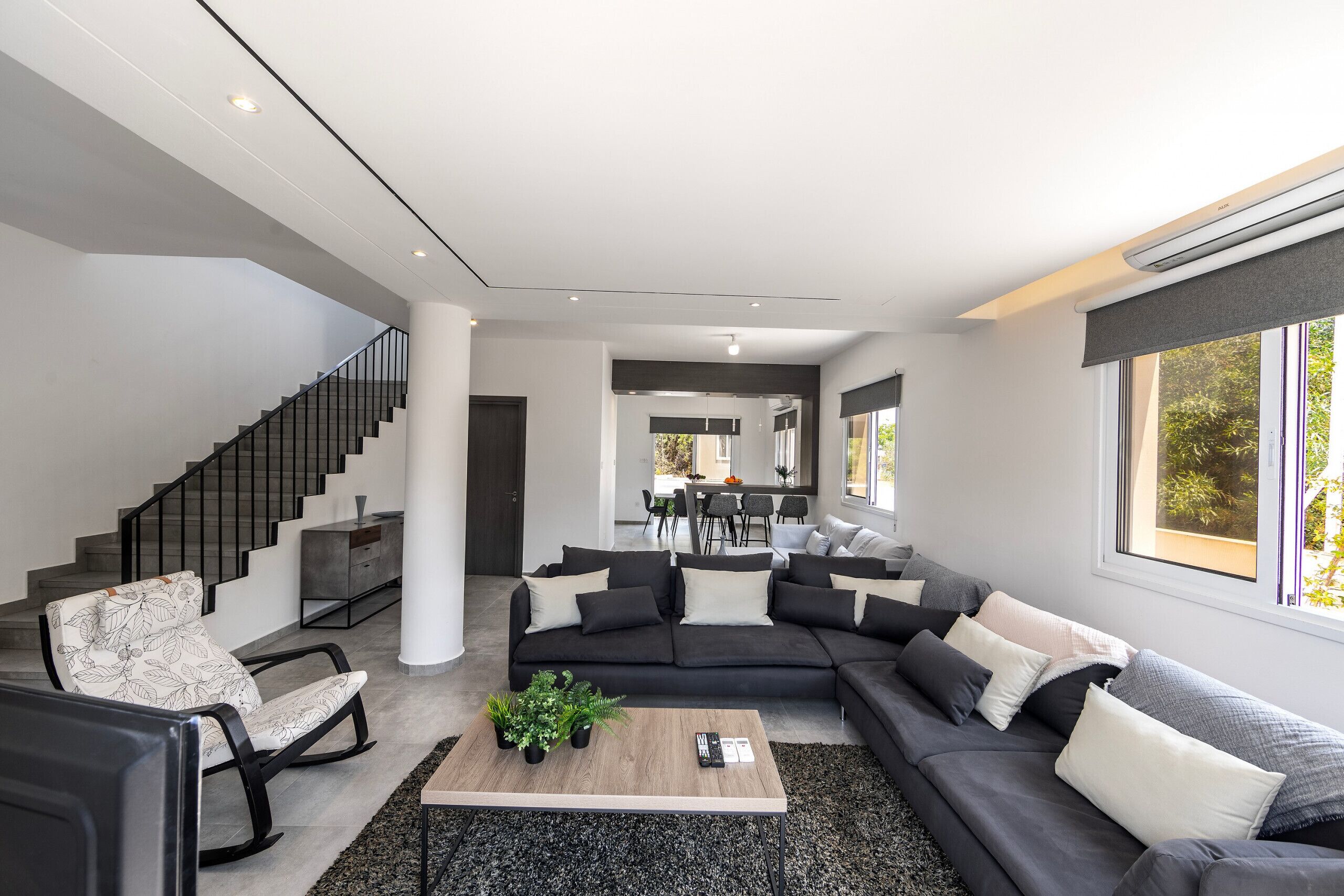 Een moderne woonkamer met een hoekbank, een salontafel en een schommelstoel.