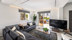 Un salon moderne avec un canapé d’angle, un téléviseur à écran plat et une table basse.