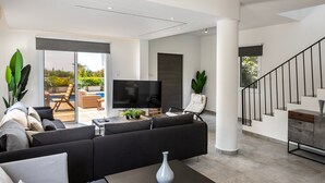 Un salon moderne avec un canapé, un téléviseur et un escalier.