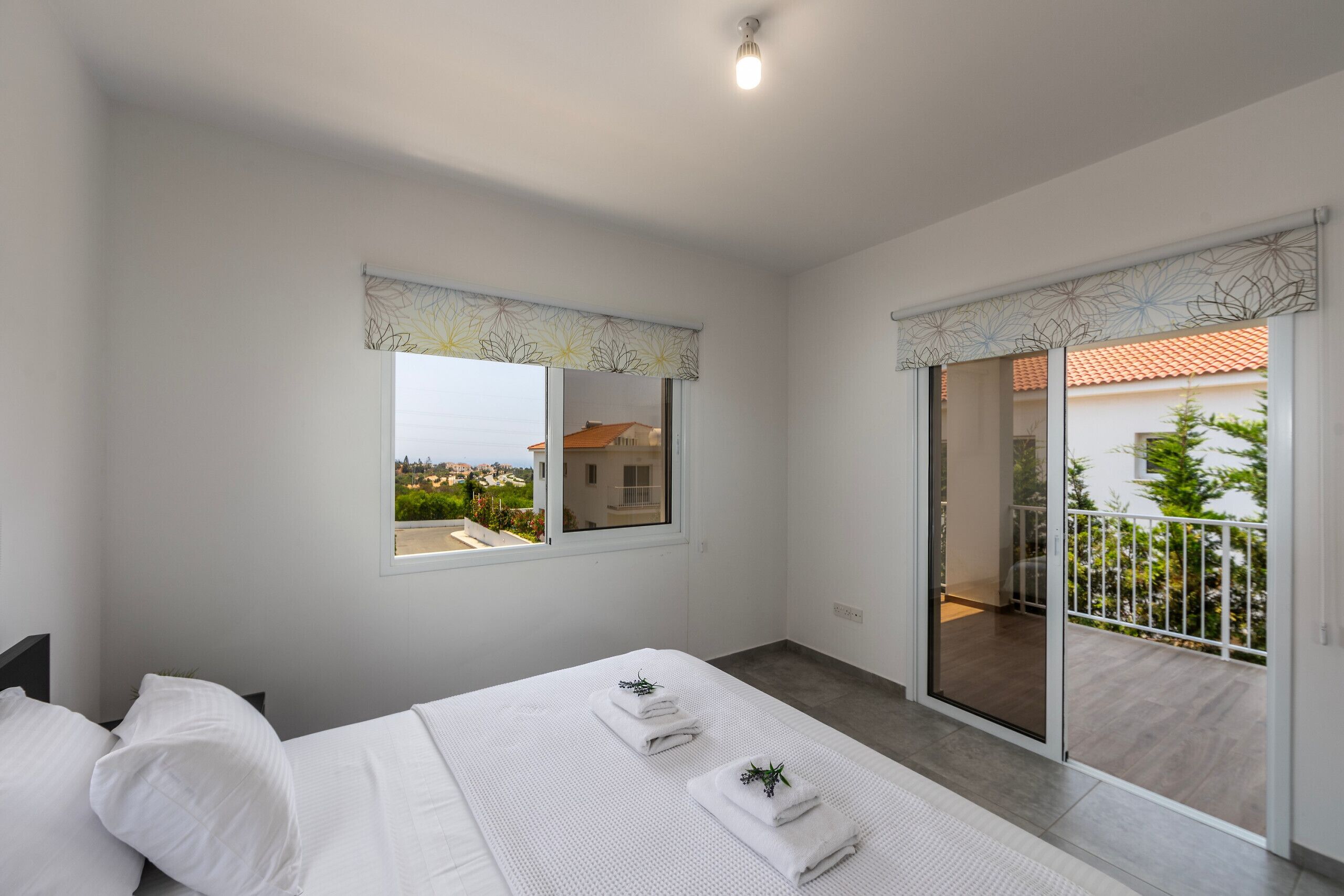 Un dormitorio con cama, ventana y puerta corrediza de vidrio que da a un balcón.