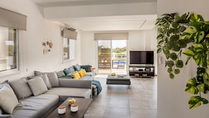 Uma sala de estar moderna com um sofá cinzento, uma mesa de centro e uma televisão.