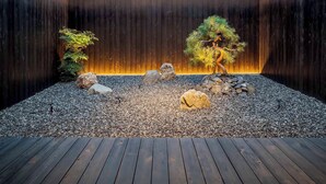 Een zen-tuin met stenen, een pijnboom en een bonsai.