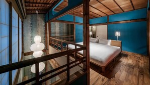Een slaapkamer met een houten plafond, een bed, een nachtkastje en uitzicht door een houten hekwerk.