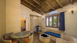 A cozy room with a round table, wicker chairs, a sofa with a blue cushion, and a small kitchenette. - Fortune Resort & Wellness Spa Bhaktapur, Nepal - Member ITC Hotels' Group (Suryabinayak)