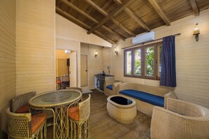 A cozy room with a round table, wicker chairs, a sofa with a blue cushion, and a small kitchenette. - Fortune Resort & Wellness Spa Bhaktapur, Nepal - Member ITC Hotels' Group (Suryabinayak)