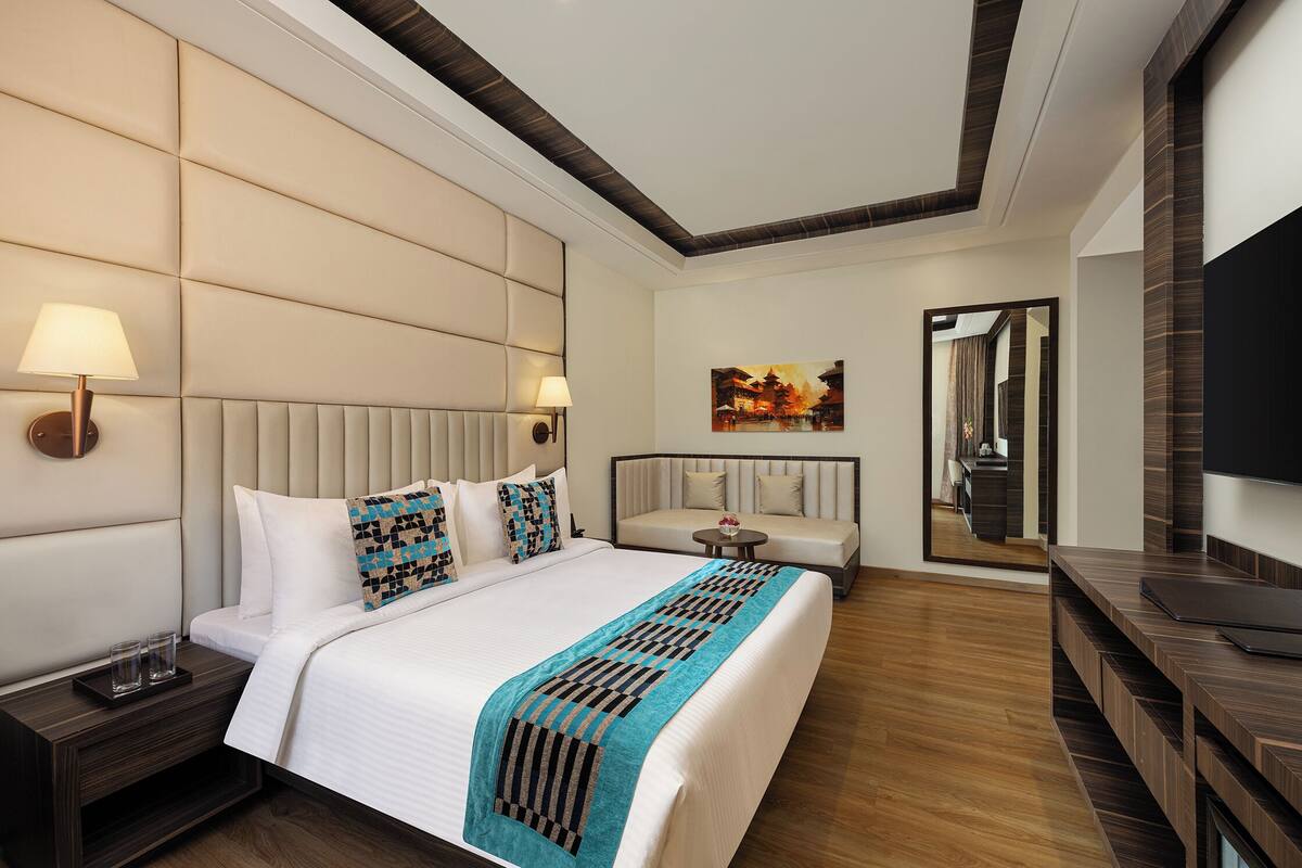 Une chambre d’hôtel avec un grand lit, un canapé, une télévision et un tableau au mur.